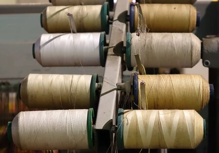 An old piece of textile manufacturing equipment with various spools of yarn