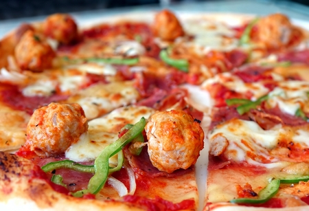 Oven baked pizza with meatballs, salami, tomatoes, cheese and fresh bell pepersの写真素材