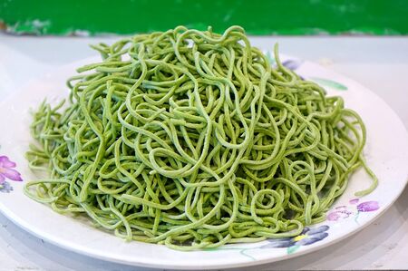 A plate with freshly made green pastaの写真素材