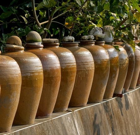 A row of large pickling jars on a garden wallの写真素材