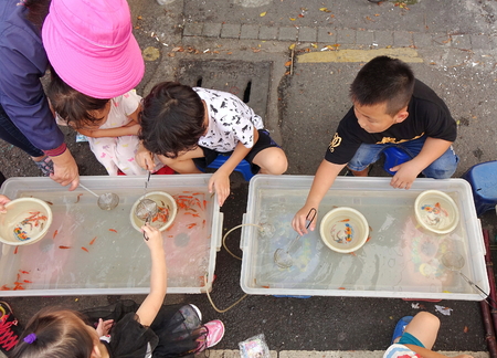 KAOHSIUNG, TAIWAN -- OCTOBER 15, 2016: Young children catch small goldfish. This is a popular children's activity at outdoor markets.のeditorial素材