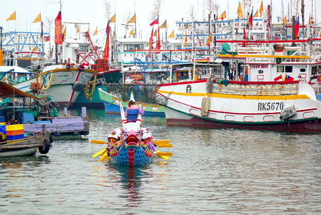 LINYUAN, TAIWAN -- MAY 28, 2017: A dragon boat team has just finished its race. In the back are fishing vessels anchored in the Zhongyun Fishing Port.のeditorial素材