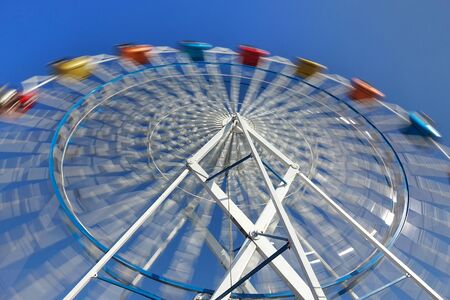 A ferris wheel with colorful cabins at a local fun fairの写真素材