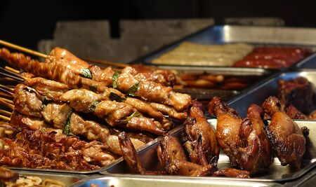 A street food stall in Taiwan offers grilled meat skewers and chicken legsの写真素材