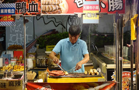 KAOHSIUNG, TAIWAN -- MARCH 2, 2018: An outdoor vendor at a night market grills fresh pork sausages.のeditorial素材