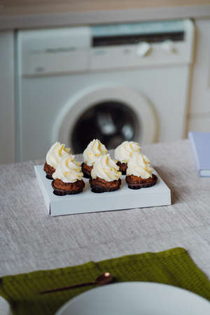 Chocolate cupcakes with whipped cream on a white plate in the kitchen