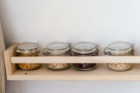 Glass jars with cereals and grains on a shelf in the kitchenの写真素材