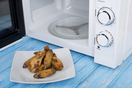 A new white microwave oven, on a blue wooden surface for heating foodの写真素材