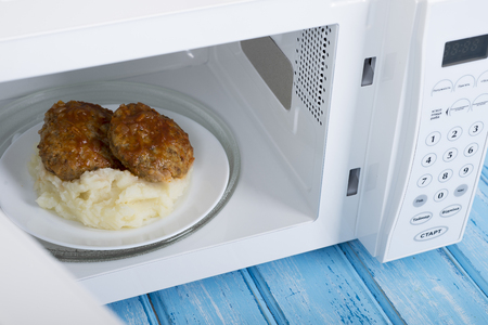 A new white microwave oven, on a blue wooden surface for heating foodの写真素材