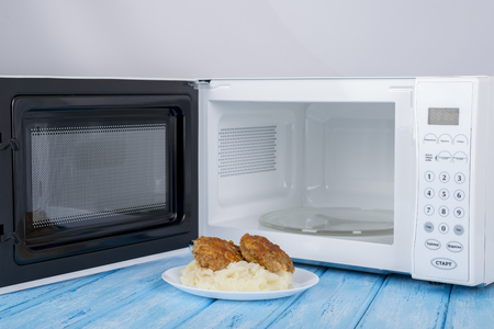 A new white microwave oven, on a blue wooden surface for heating foodの写真素材