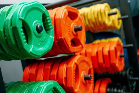 Dumbbells of different sizes. dumbbells in the fitness room. Dumbbells of orange, green and yellow....