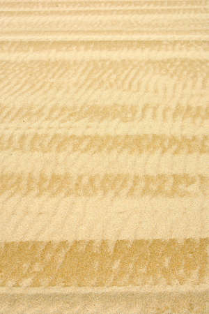 Waved beach sand background with old weathered vehicle tracks.  の写真素材