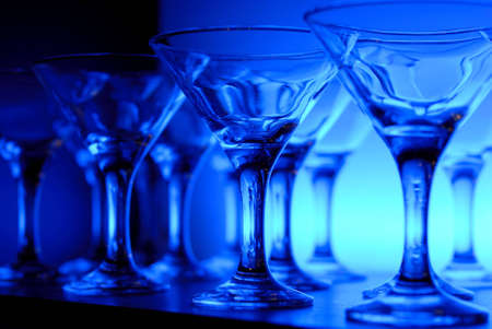 Wineglasses arranged in rows on the table in blue lightの写真素材
