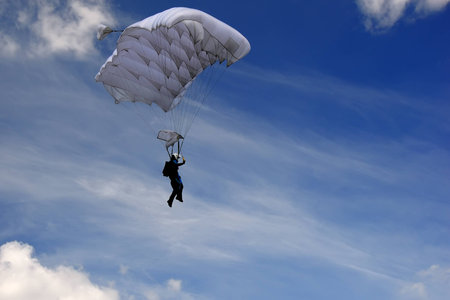 Skydiver moving down in high speed just before landing. Background with blue sky with clouds.
