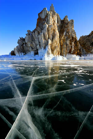 Surface of frozen lake Baikal. Cliff rock with icicles.
