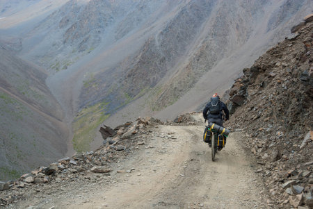 Bicycle tourist riding down the bumpy gravel mountain roadの写真素材