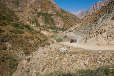 Big tank-truck and small car on the steep precipitous mountain roadの写真素材