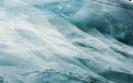 Cracked black ice of frozen lake. Nature abstract background.の写真素材
