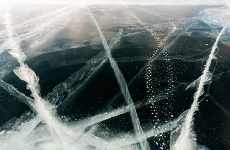 Winding trace of studded bicycle tires on the black ice surface of frozen lake. Nature abstract backgroundの写真素材