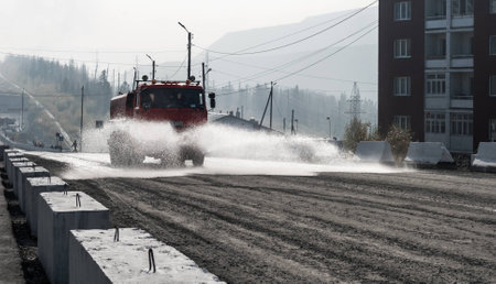 Watering machine splashing water on the dusty gravel roadの写真素材