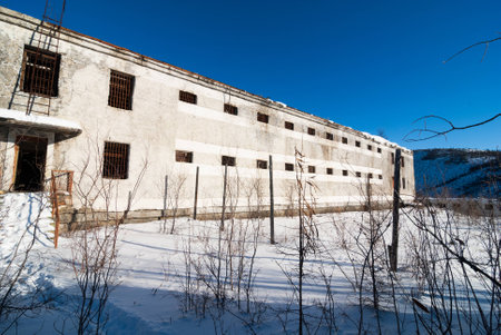 Exterior of housing of old decayed abandoned prison in Kolyma in sunlightの写真素材