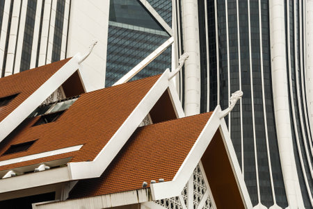 Mirrored wall of big skyscraper and orange roof of lower building. Abstract city background.の写真素材