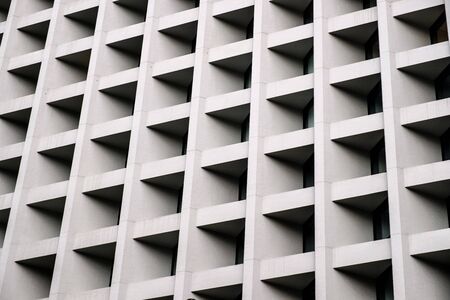 Gray concrete wall with many equal square windows. Abstract city architecture background.の写真素材