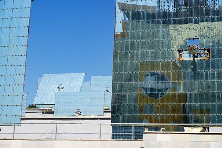 Group of heliostats â plain mirrors on the special field, which turn with the Sun and reflect sunlight toward one target â solar furnace (seen in reflection). Abstract science background. の写真素材