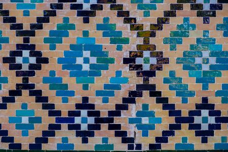Tin-glazed pottery tiled wall in ancient mosque in Uzbekistan. Abstract art background.の写真素材