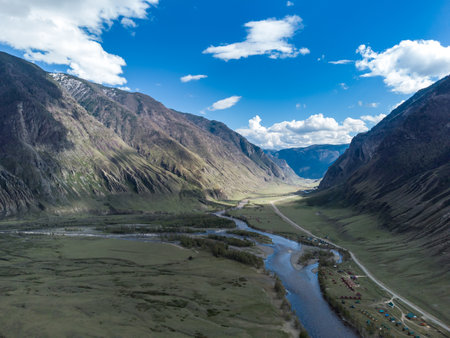 Scenic view of Chulyshman River Valley in Altai. lush green vegetation and towering mountains under cloudy sky. Travel and landscape photography.の写真素材