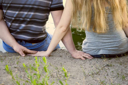 The hands of a loving couple intertwining behind backsの写真素材
