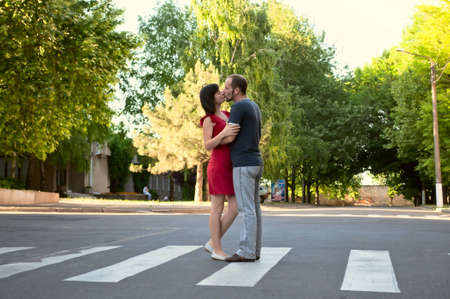 The loving couple stand on a pedestrian crossing in the middle of street and kissesの写真素材