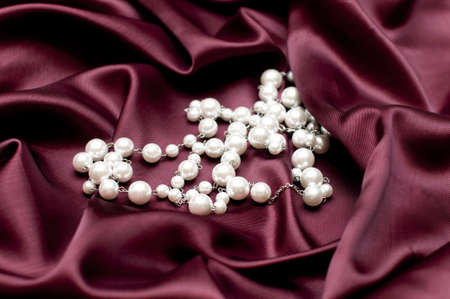 shiny white pearls on ruby satin backgroundの写真素材