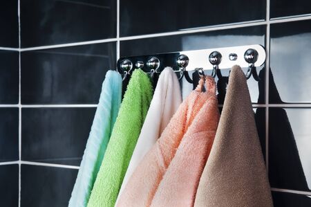 hanging bright towels on the background of black tileの写真素材