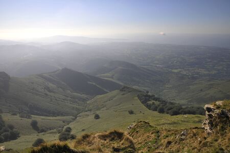 Misty landscape with little mountains and blue sky at the end of afternoonの写真素材