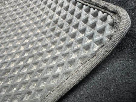 Textured rubber car mat features a diamond pattern, displaying signs of wear and dirt, emphasizing its durability and practical use in vehicle interiorsの写真素材