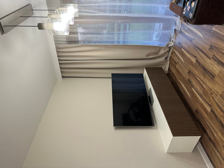 Contemporary living space showcases a flat-screen television on a minimalist cabinet, with soft curtains and polished wooden floors, enhancing the inviting ambianceの写真素材