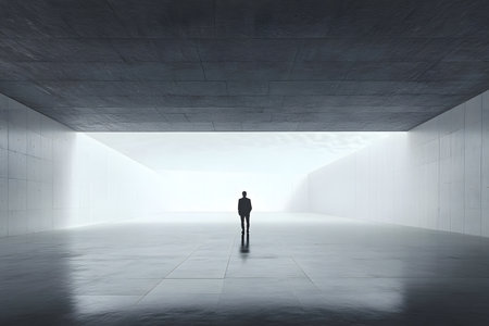 A lone individual stands in an expansive, minimalist area characterized by smooth concrete surfaces and gentle lighting, creating a serene atmosphere for reflectionの素材
