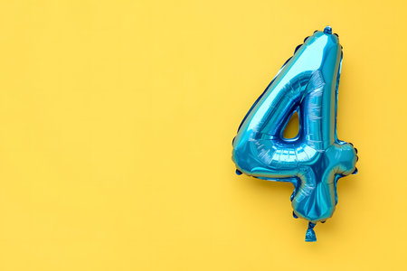Pastel colors, the letter 4 from a blue foiled balloon on a pastel yellow background with space for text.の素材