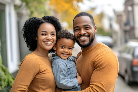 A happy family standing in front of their home, feeling secure with home insurance coverage, smiling and united.の素材