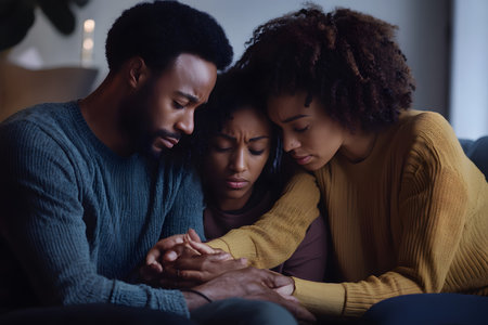 A grieving family sitting together at home, providing emotional support to each other during a difficult moment.の素材