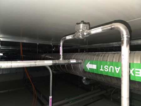 Ventilation system with metallic ducts and pipes, featuring directional exit signage, highlighting...
