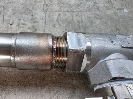 Detailed close-up of a metallic pipe fitting with threaded connection, highlighting the...