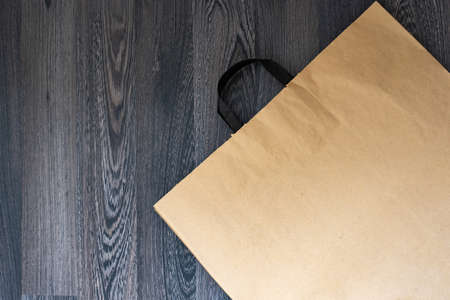 Kraft paper bag on dark wooden backgroundの写真素材