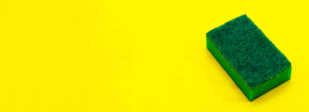 A dish washing sponge isolated on a yellow background close up with a blank space for your textの写真素材