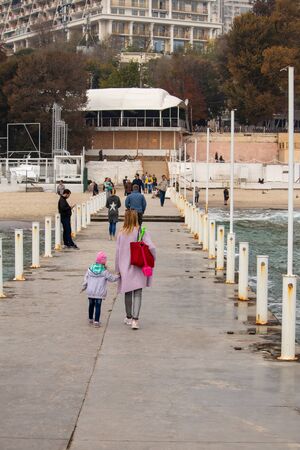 Ukraine, Odessa - 10.17.2019 - People stroll in the autumn on the pier by the sea - photoのeditorial素材