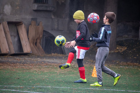 A young football coach trains beginner players during a practice session. The photo captures the energy and enthusiasm of children learning the basics of football. The training takes place outdoors in Odessa, Ukraine. The image is suitable for editorial use, illustrating youth sports and development.の写真素材