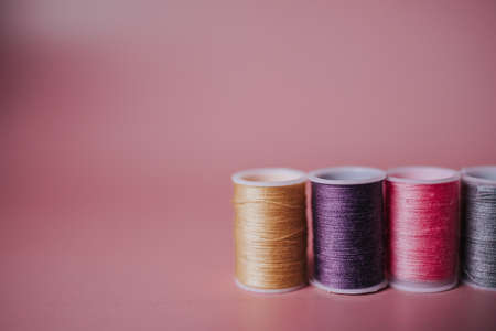 four multicolored threads on a pink backgroundの写真素材