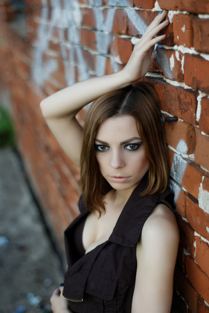 Caucasian blond woman standing behind brick wallの写真素材