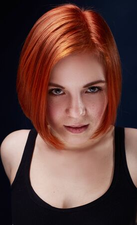 Close-up portrait of Young woman with red hair on a black backgroundの写真素材